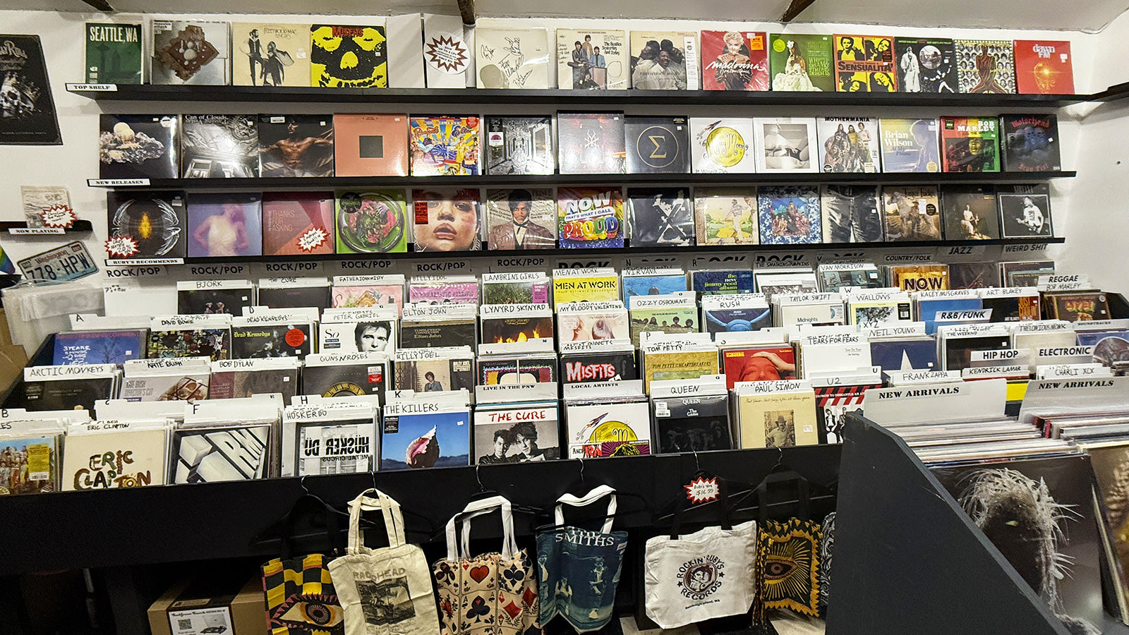 Shelf displaying a collection of CDs and DVDs with visible branding and packaging at Rockin' Ruby's Records on Bainbridge Island, WA
